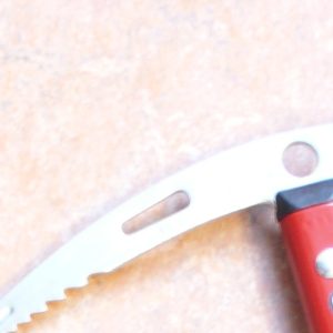 Close-up of an ice axe pick head — forged adze and serrated pick blade, no brand markings visible