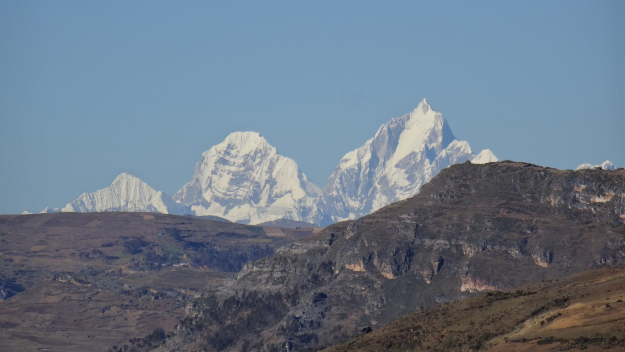 Snow-covered peaks of Siula Grande and Yerupaja rising above the Andean foothills, Cordillera Huayhuash, Peru