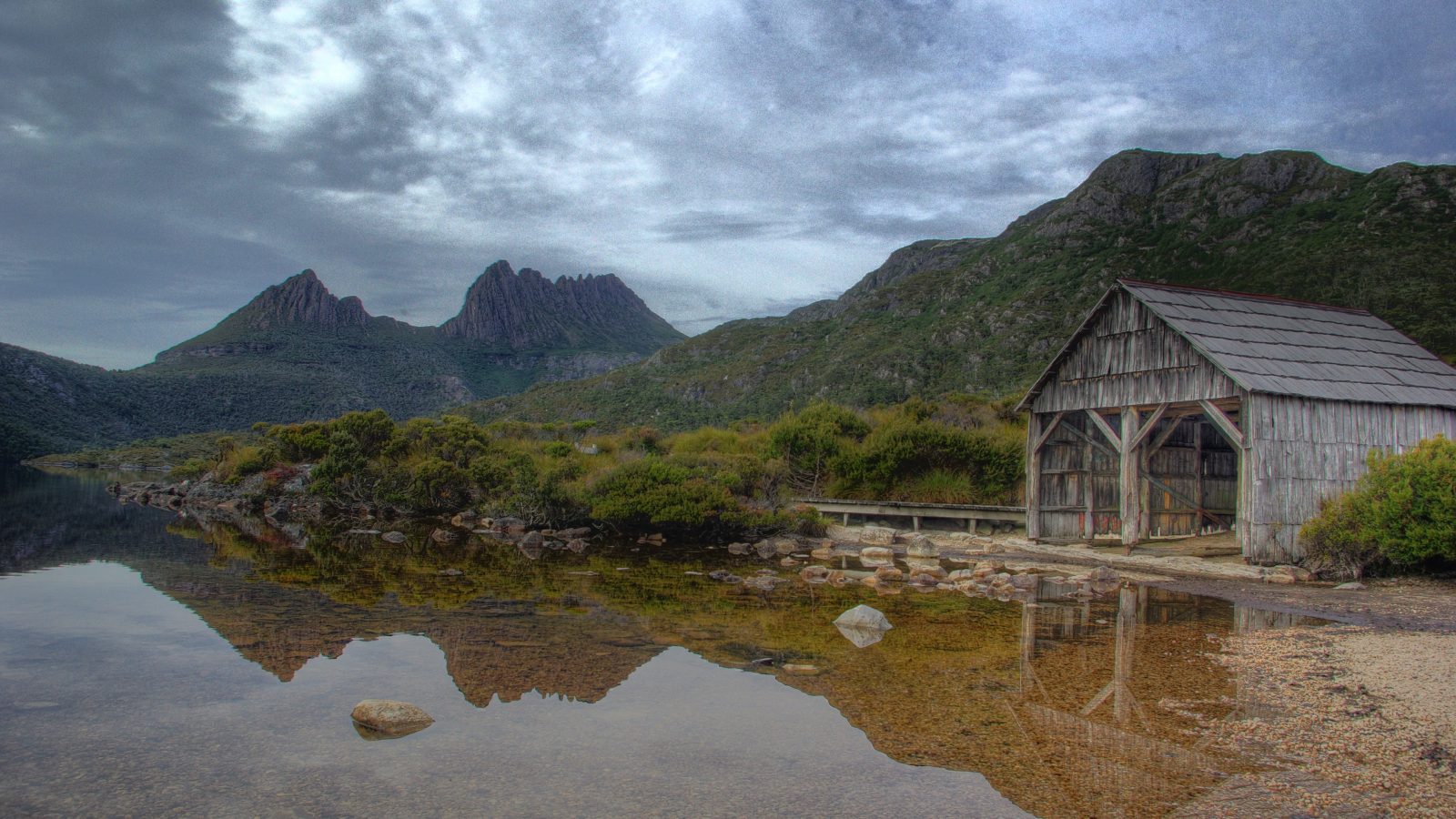 Cradle Mountain's jagged peaks reflected in Dove Lake with the historic wooden boat shed, Tasmania, Australia